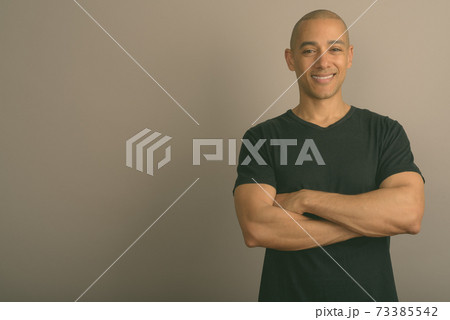 Handsome bald man wearing black shirt against gray background Handsome bald man wearing black shirt against gray background 73385542