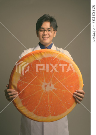 Young handsome Asian man doctor wearing eyeglasses against gray background 73385826