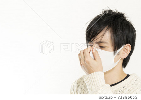 マスク姿の男性/頭痛で頭を抱える/具合が悪い独身男性/	 73386055