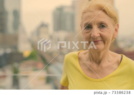 Beautiful senior woman with blond hair against view of the city Beautiful senior woman with blond hair against view of the city 73386238