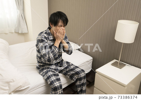 ベッドルームにてパジャマ姿でくしゃみをする男性 ベッドルームにてパジャマ姿でくしゃみをする男性 73386374