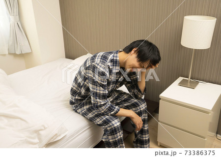 寝起きに発熱がわかり、体調が悪くなって会社に行けないパジャマ姿の男性 寝起きに発熱がわかり、体調が悪くなって会社に行けないパジャマ姿の男性 73386375
