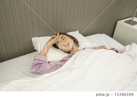 病気で寝込んでいる女性/体調の悪い女性/ベットに寝ている美しい女性 73386399