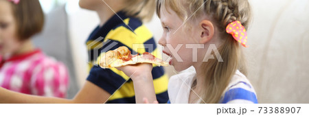 Little girl and children hold piece of pizza in their hands. 73388907