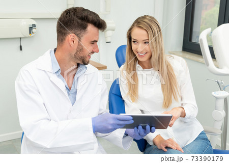 Dentist showing teeth x-ray on tablet screen 73390179