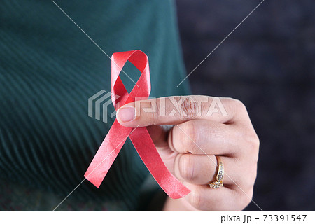 women hand holding red HIV ribbon isolated on black  73391547