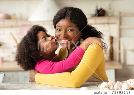 Happy Mother's Day. Little Black Girl Kissing Her Happy Mom In Kitchen 73392113