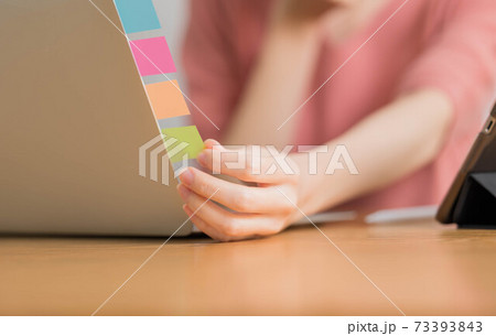 ふせんを取る若い女性の手 73393843