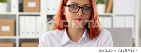 Calm red woman working on notebook in office Calm red woman working on notebook in office 73394137