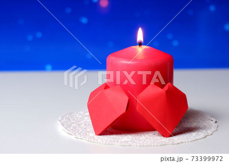 Couple of 3D red paper hearts, burning pink candle on white openwork paper napkin, blue bokeh snow background closeup view selective focus. Love, Valentine's, women's day, relations, romantic concept 73399972