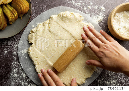 Kneading dough by female hands. Cooking pear tart. Homemade baked goods. 73401134