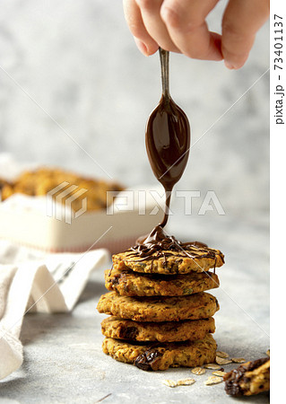 Oat cookies. Female hand pouring chocolate on homemade cookies. 73401137