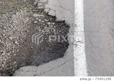pothole with spoiled asphalt pavement with white markings close up, pit on the side of the road, danger on the highway, nobody. 73401198