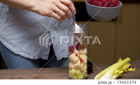 Woman pouring raspberries in blender glass Woman pouring raspberries in blender glass 73401574