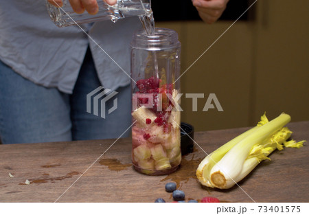 Woman pouring water in blender glass 73401575
