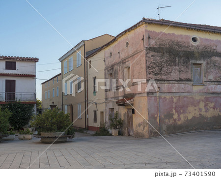 Street in old town of Tortoli with yellow pink houses and green plants. Sardinia, Italy, summer afternoon Street in old town of Tortoli with yellow pink houses and green plants. Sardinia, Italy, summer afternoon 73401590