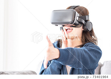 リビングでヘッドマウントディスプレイを付けて仮想現実（VR）を楽しむ女性 73401964