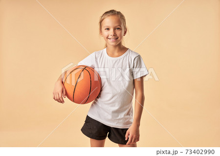 Cheerful girl basketball player holding game ball 73402990