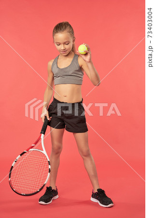 Adorable female child holding tennis racket and ball Adorable female child holding tennis racket and ball 73403004