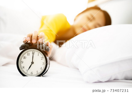 Young asian woman wake up early in morning. She lying on bed and trying turn off alarm clock Young asian woman wake up early in morning. She lying on bed and trying turn off alarm clock 73407231