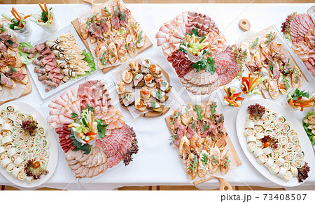lots of meat snacks on a long white table on plates of trays lots of meat snacks on a long white table on plates of trays 73408507