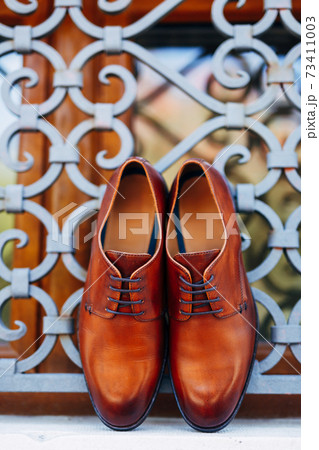 New brown mens shoes by the window with metal bars with shallow depth of field. New brown mens shoes by the window with metal bars with shallow depth of field. 73411003