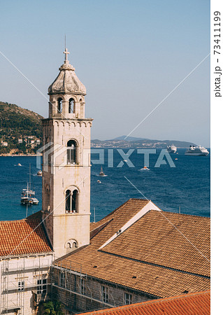 The bell tower of the Dominican monastery on the background of modern Dubrovnik, Croatia. The bell tower of the Dominican monastery on the background of modern Dubrovnik, Croatia. 73411199