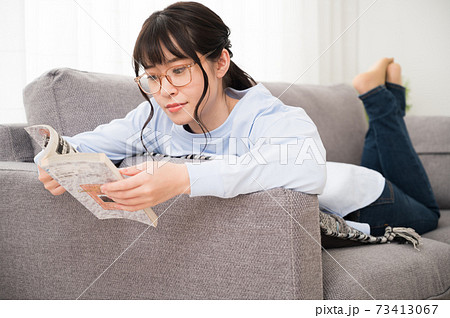ソファーで寝転がってコミックを読む女性 73413067