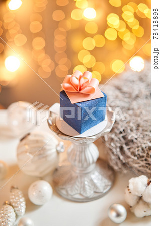 Mini mousse pastry dessert with blue velour. garland lamps bokeh background. In the form of gift box, ribbons of chocolate. Modern european cake. French cuisine. Christmas theme Mini mousse pastry dessert with blue velour. garland lamps bokeh background. In the form of gift box, ribbons of chocolate. Modern european cake. French cuisine. Christmas theme 73413893