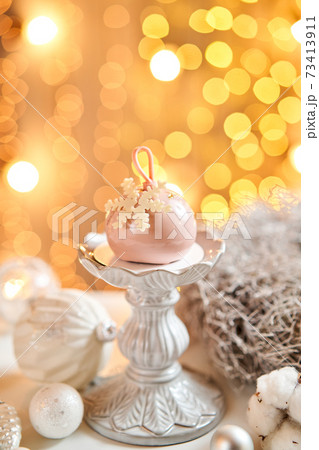 Mini mousse pastry dessert with pink glazed. Garland lamps bokeh on background. Modern european cake. French cuisine. Christmas theme. Snowflake 73413911