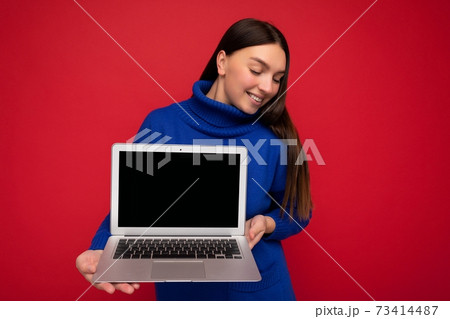 Photo of smiling pretty happy beautiful young brunet woman holding computer laptop looking down 73414487