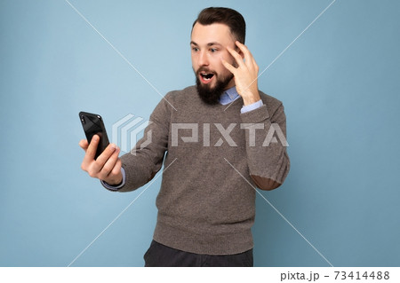 Photo of stunned amazed positive handsome young brunette unshaven man with beard wearing casual grey 73414488