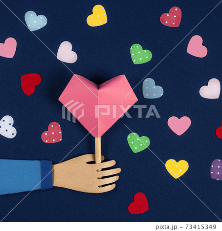 Hand holding a Paper Origami Heart. Valentine's Day card, paper cutting. 3D Paper art and origami style Hand holding a Paper Origami Heart. Valentine's Day card, paper cutting. 3D Paper art and origami style 73415349