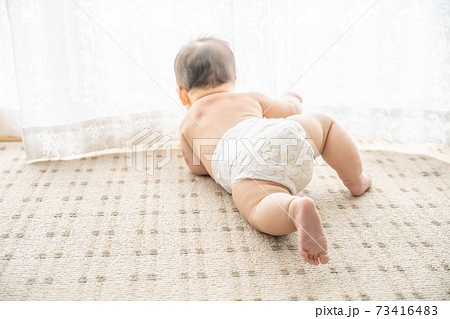 窓辺ではいはいをしている後ろ姿の裸の赤ちゃんの写真素材