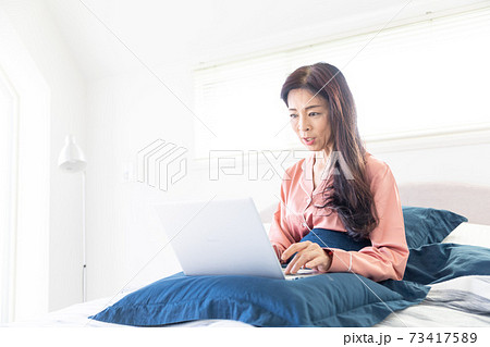ベッドでパソコンをする女性 ベッドでパソコンをする女性 73417589