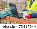 Woman civil engineer holding cup of coffee and using laptop at outdoor 73417944