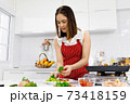 Asian woman chef in red apron putting parsley on steak in kitchen. Concept woman preparing meal at home. 73418159