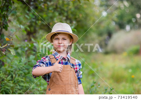 Portrait of one cute boy in a hat in the garden with a red apple, emotions, happiness, food. Autumn harvest of apples. Portrait of one cute boy in a hat in the garden with a red apple, emotions, happiness, food. Autumn harvest of apples. 73419540