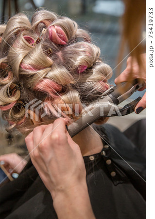 Hairdresser makes hair styling woman in the salon. Hairdresser makes hair styling woman in the salon. 73419733