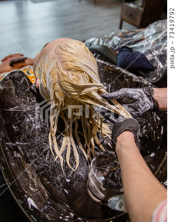 Hairdresser washing hair for a blonde girl. Hairdresser washing hair for a blonde girl. 73419792