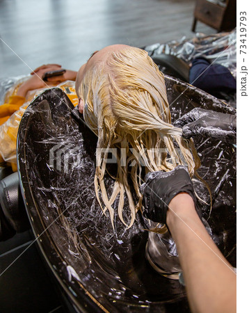Hairdresser washing hair for a blonde girl. Hairdresser washing hair for a blonde girl. 73419793
