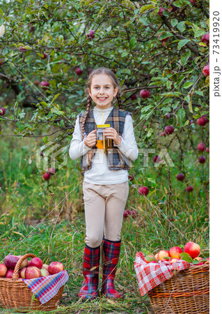 Portrait of a cute girl in a farm garden with a red apple. Portrait of a cute girl in a farm garden with a red apple. 73419920