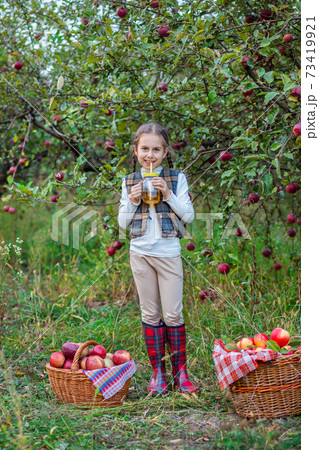 Portrait of a cute girl in a farm garden with a red apple. Portrait of a cute girl in a farm garden with a red apple. 73419921