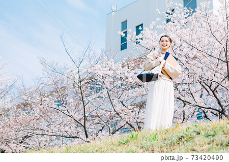 桜並木の土手を歩く女性の写真素材