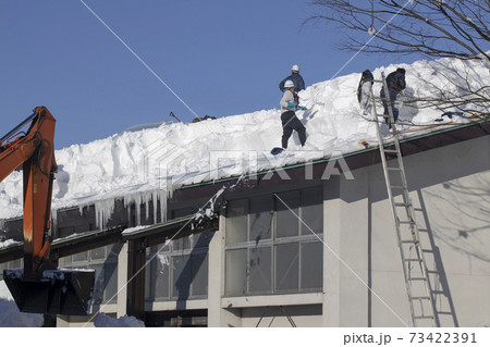屋根の雪下ろしをする人たち	 73422391