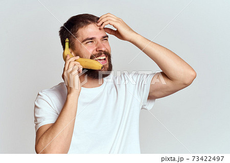 Cheerful man with a banana in his hands on a light background fun emotions Cropped view Copy Space Cheerful man with a banana in his hands on a light background fun emotions Cropped view Copy Space 73422497