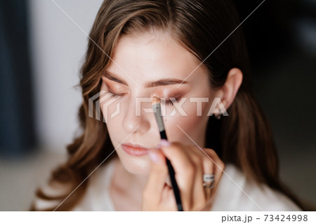 A beautiful young woman with long hair doing makeup for a wedding or photo shoot 73424998