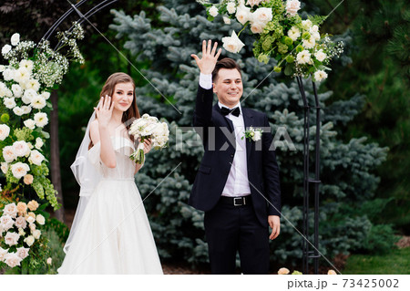 wedding ceremony in an arch of living flowers. newlyweds show hands with rings wedding ceremony in an arch of living flowers. newlyweds show hands with rings 73425002