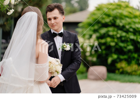 wedding ceremony in arch of living flowers. the groom listens to the bride's vow 73425009