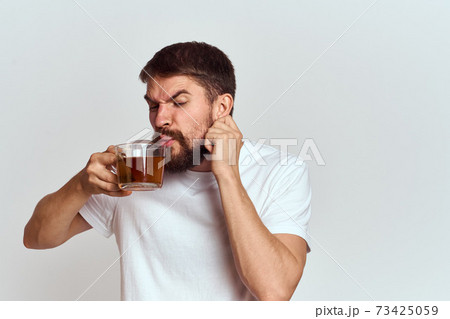 man with a cup of tea in a bag on a light background Hot drink cropped view model man with a cup of tea in a bag on a light background Hot drink cropped view model 73425059